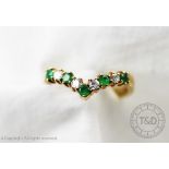 An emerald and diamond wishbone half eternity ring, designed as alternating emeralds and diamonds,