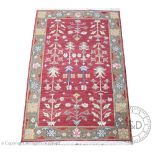 A modern machine made wool rug, worked with slender slowers aganist a red ground,
