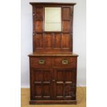 An Edwardian oak hall stand in the Arts and Crafts manner, raised mirror back with four brass hooks,