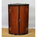 A George III oak and mahogany cross banded bow front corner cabinet,