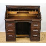An early 20th century roll top oak estate desk, the top opening to reveal a fitted interior,