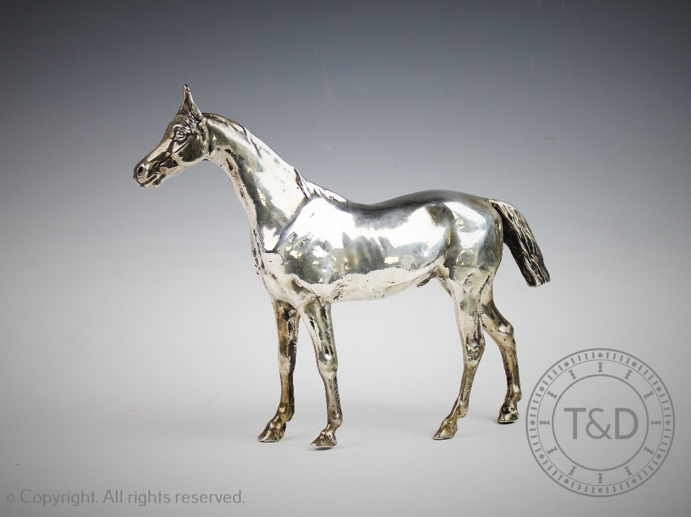A sterling silver model of a horse, realistically designed standing with textured mane and tail,