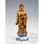 A Chinese hard stone carving of Buddha, modelled standing holding a lotus with carved Wan to chest,