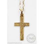 A yellow metal cross pendant with scroll engraved detail, stamped indistinctly,