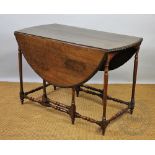 An early 20th century oak gate leg table, oval top with an oak leaf carved edge, on turned legs,