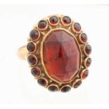 Golden ring with garnet, 585/000. Ring with oval faceted grain decorated with a border with small