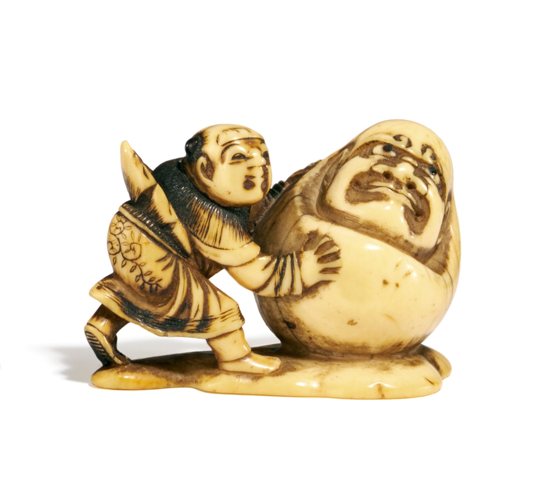 NETSUKE: KARAKO EINEN SCHNEE-DARUMA VOR SICH HER SCHIEBEND. Japan. 19. Jh. Elfenbein, Haarknoten und