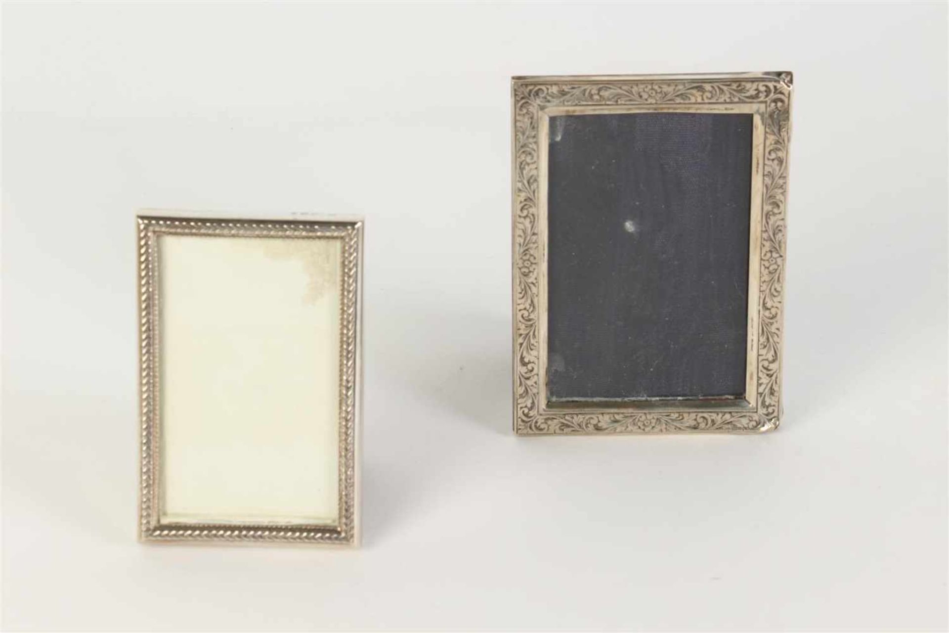 Twee fotolijstjes met zilveren montuur. Afm: 9 x 6 en 10.7 x 7.7 cm.