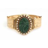 A 14 krt yellow gold stiff bracelet set with a centrepiece of carved oval jade with a rim of