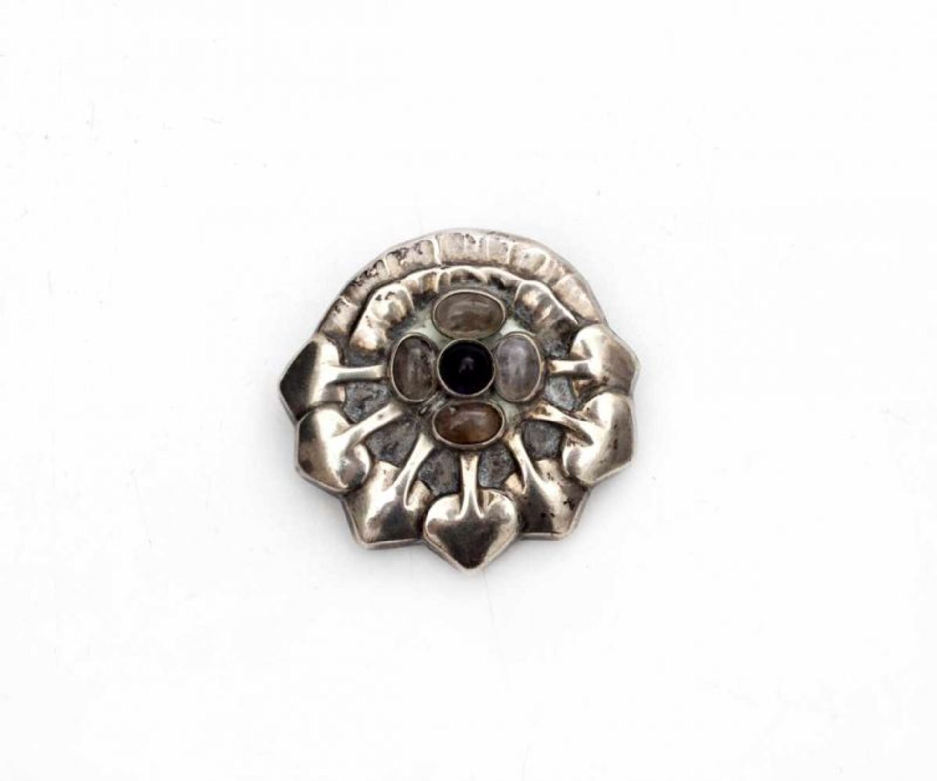 Georg Jensen (1866-1935) A hammered silver brooch with rock crystal and granate, floral design,