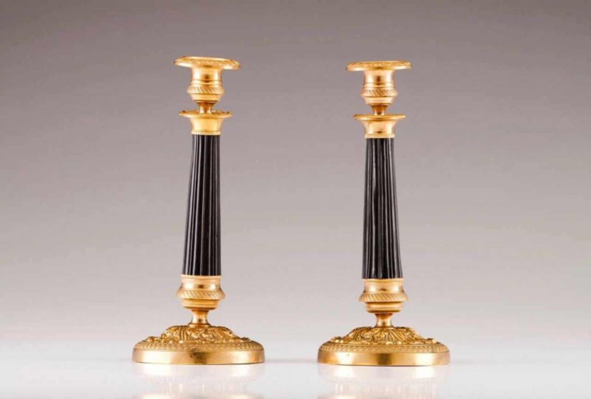 A pair of Restoaration candlesticks Patinated and gilt bronze decorated in relief Fluted stem, top