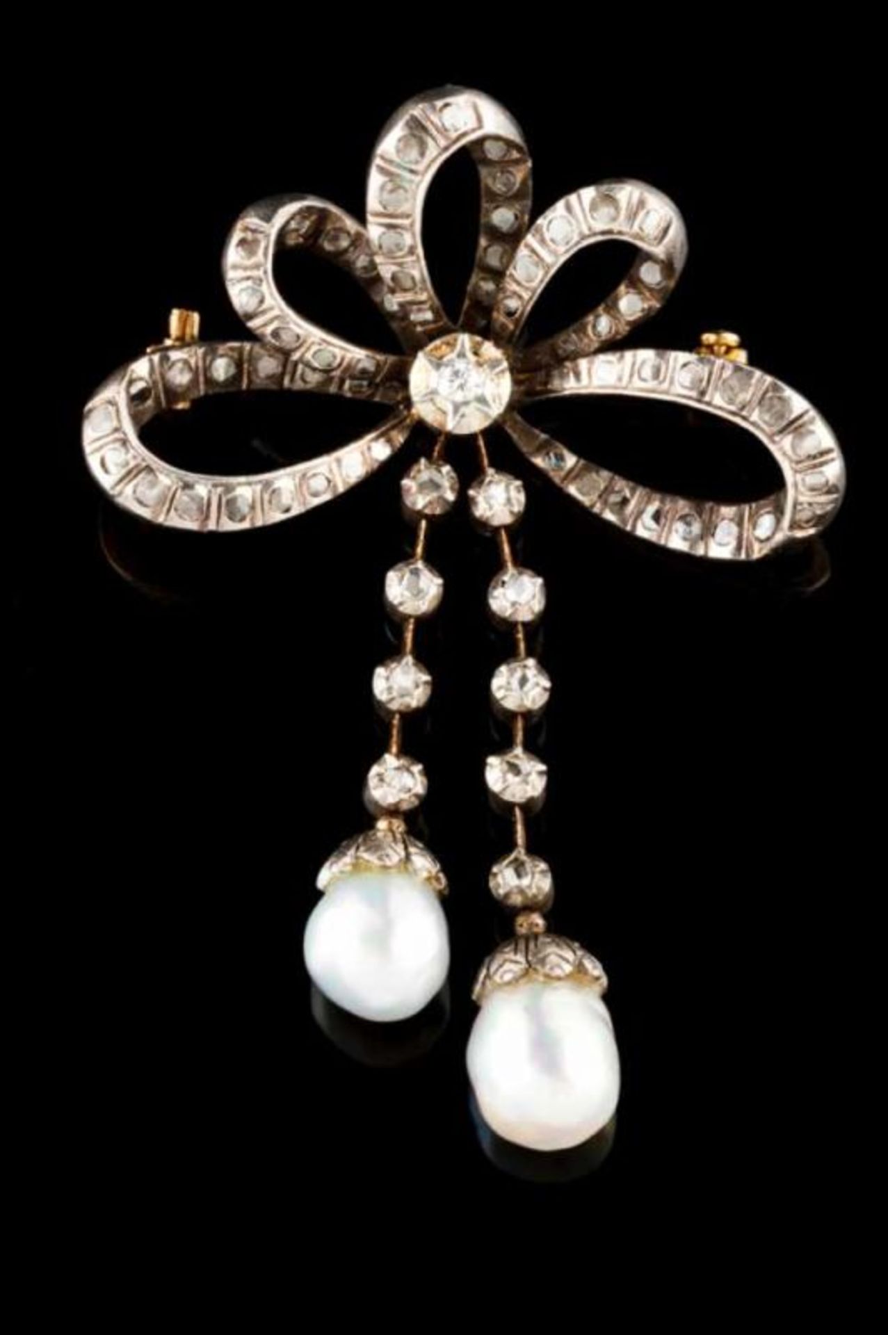 A brooch Silver and gold Designed as a ribbon with two pendants Set with rose cut diamonds, one