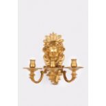 A pair of three-light wall sconces in the Regence style Chased gilt bronze Decorated with masks