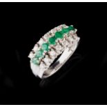 A gem-set ring Set in white gold with seven round cut emeralds and 14 brilliant cut diamonds (ca.