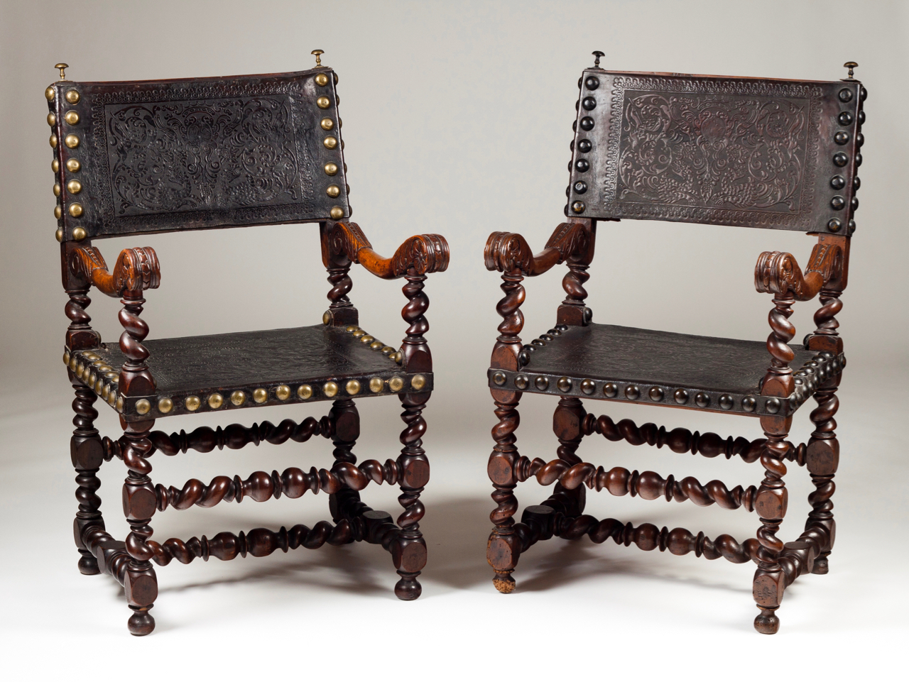 A set of two armchairs Walnut Engraved leather backs and seats with brass pins Decorated with