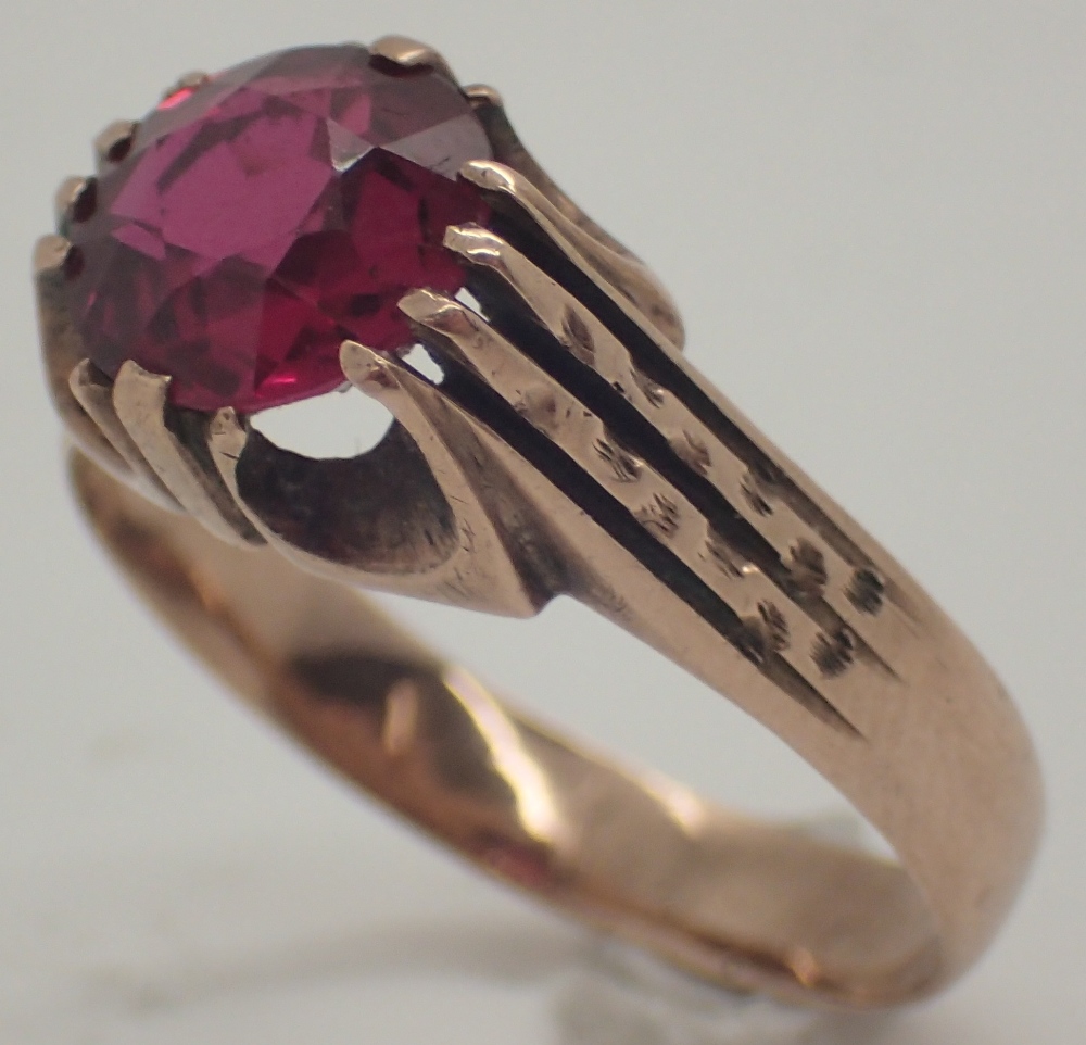 Large circular cut faceted ruby on an unusual yellow metal ring ruby approximately 1.5ct size U 5.