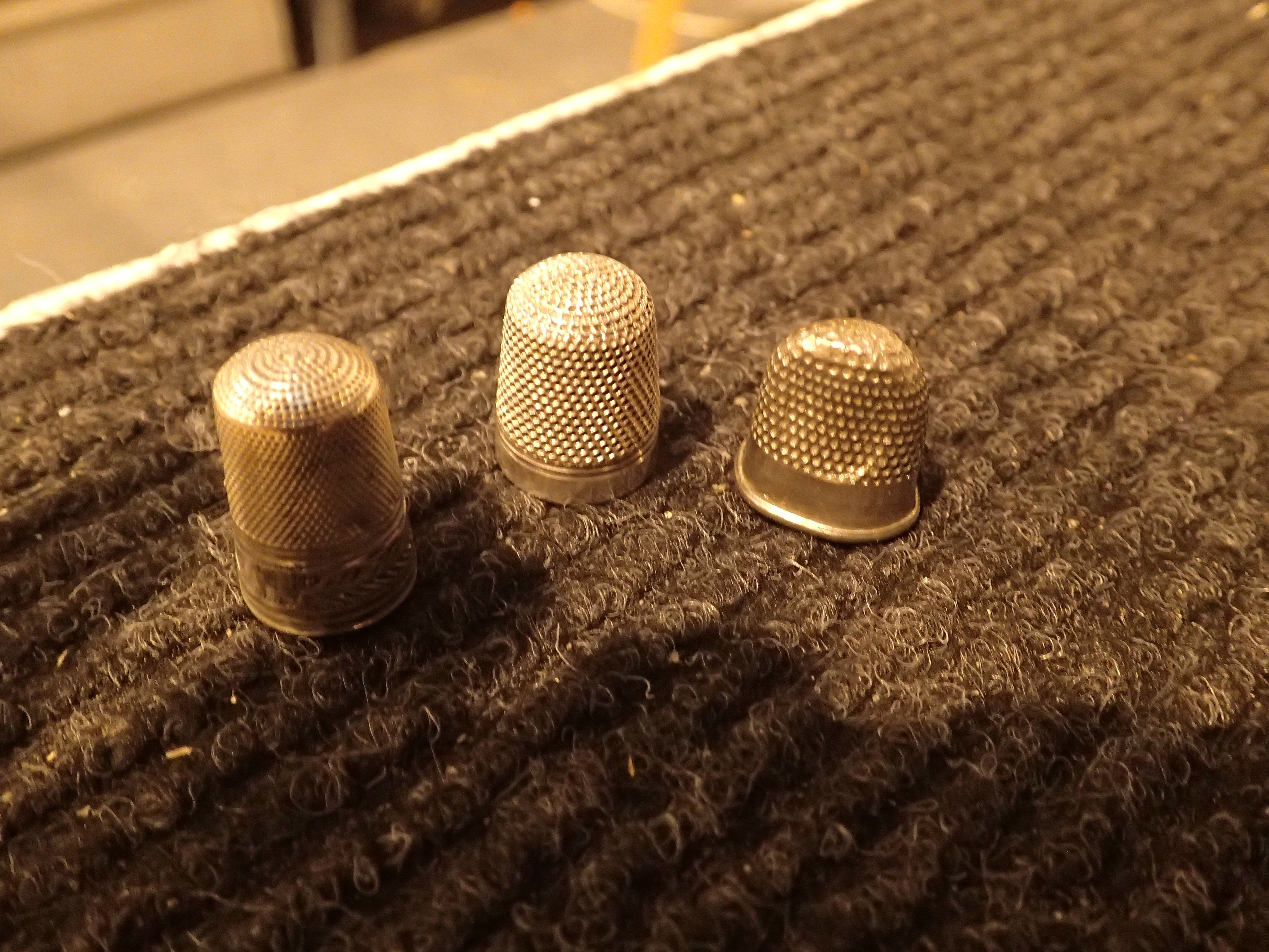 Three white metal thimbles including fingernail example