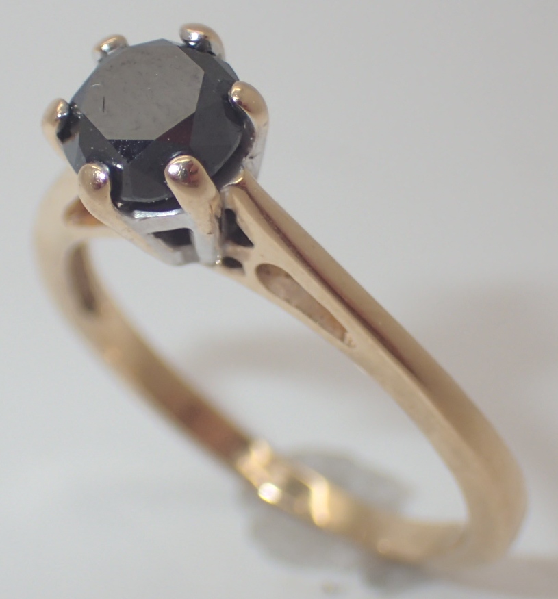 Black diamond solitaire ring in a white gold setting on a yellow gold shank size N approximately 0.