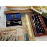 Two boxed sets of drawing instruments and a sheet of vintage nibs