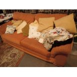 Terracotta upholstered three seat settee with scatter cushions