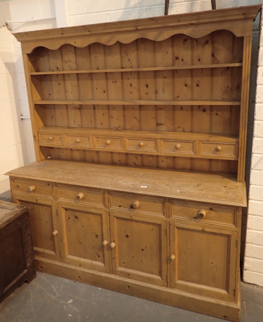 Large pine dresser with four drawers over four cupboards with plate rack containing six drawers 182
