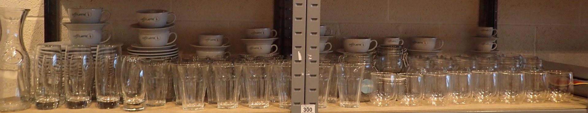 Two shelves of caffelatte cup saucers plates glasses and kilner jars