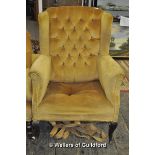 A winged buttonback armchair on cabriole legs.