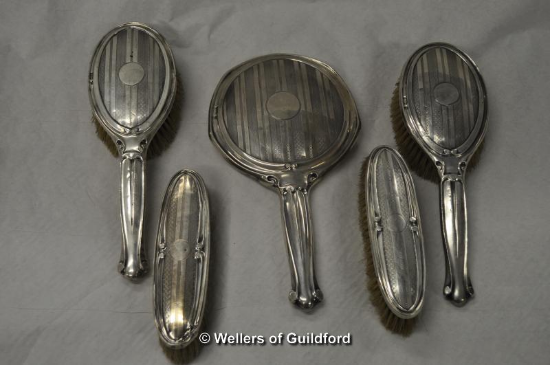 A silver dressing table set comprising hand mirror, two hair brushes and two hat brushes, Chester