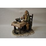 A Capo di Monte style figure of musician seated at a table, 30cm long.