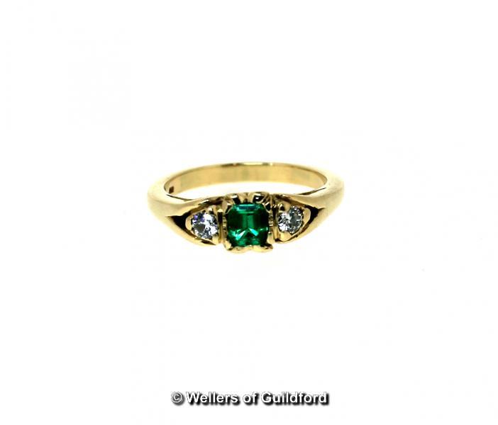 Three stone emerald and diamond ring, central emerald cut emerald with a round brilliant cut diamond