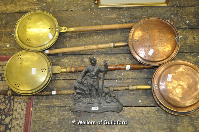 A cast iron door stop; two copper warming pans and two brass examples.