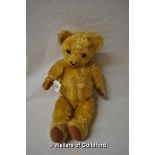 A golden haired teddy bear with stitched nose and mouth, felt pads.