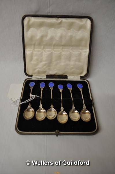 A set of six white metal coffee spoons with blue enamel terminals, stamped 'silver', cased.