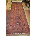 A Persian runner with ten central medallions, multiple borders, madder ground, 220 x 88cm.