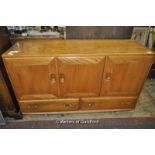 An Ercol sideboard with three cupboard doors over drawers, 129cm wide.