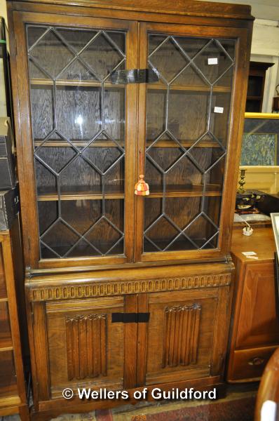 An oak bookcase with astragal glazed doors over linenfold panelled doors, 191cm x 92cm