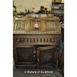 An oak bureau with linenfold panel flap over single drawer with cupboard below, 76cm wide.