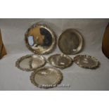 A graduated set of three circular silver plated trays with grapevine borders; three further silver