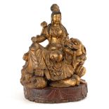 Große Guanyin auf Löwen sitzend. China, wohl Ende 19. Jh. Holz, goldfarben gefaßt. Massive