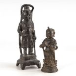 2 Bronzefiguren mit dunkler Patina. Stehende Figur auf Sockel mit Stab und um den Körper wachsende