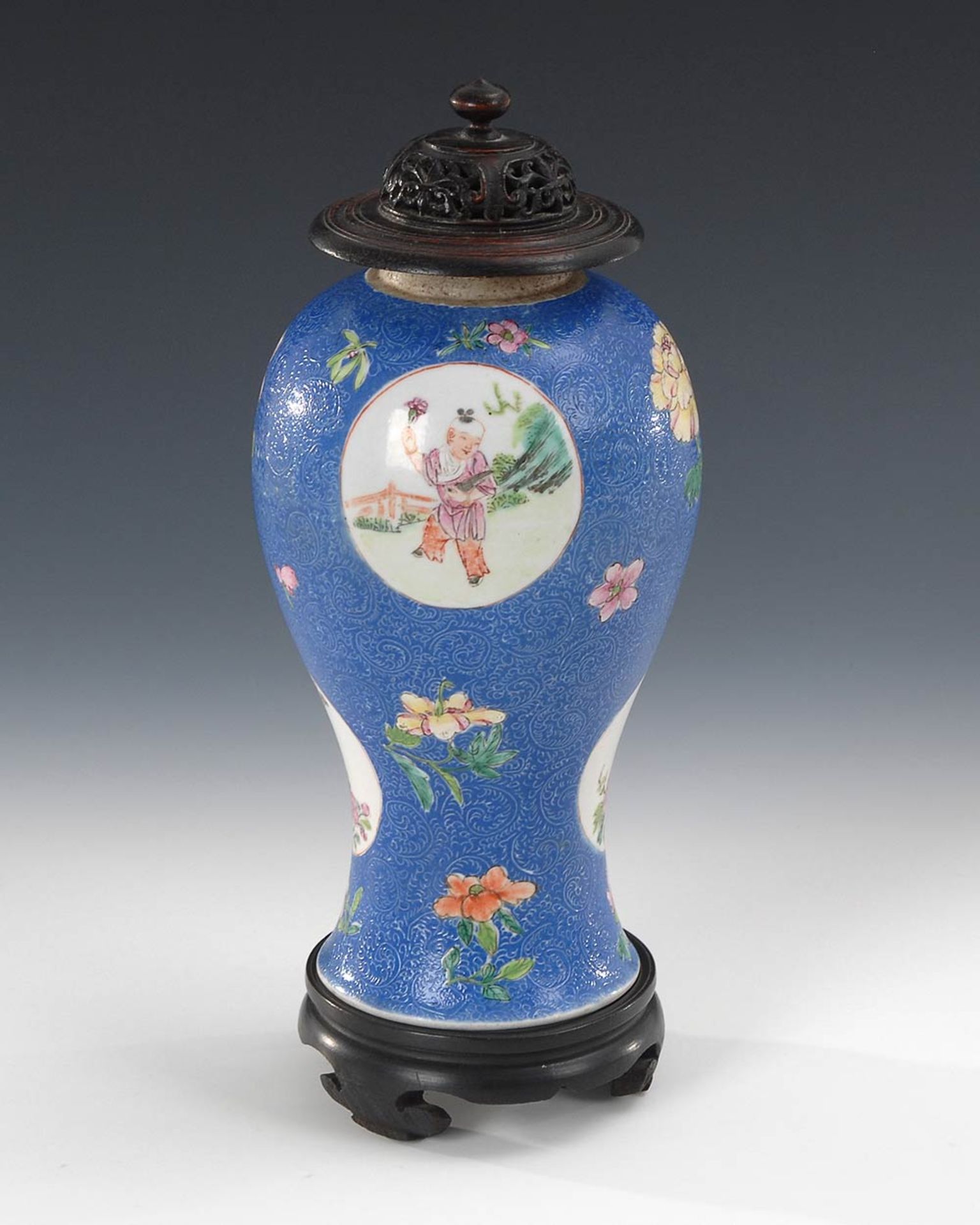 Blaue Vase auf Holzsockel. Porzellan. Balusterform mit schlankem Fußteil. Blaue Glasur mit geprägtem
