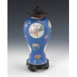 Blaue Vase auf Holzsockel. Porzellan. Balusterform mit schlankem Fußteil. Blaue Glasur mit geprägtem