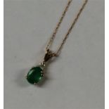 An emerald and diamond pendant on fine link chain.