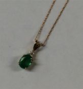 An emerald and diamond pendant on fine link chain.