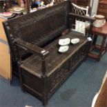 An oak tilt top carved settle.