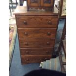 A small narrow oak chest of four drawers.