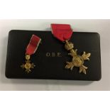 A boxed OBE medal on ribbon together with miniatur