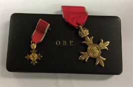 A boxed OBE medal on ribbon together with miniatur