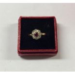 A ruby and diamond circular cluster ring in 18 car