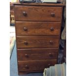 A narrow chest of five drawers.